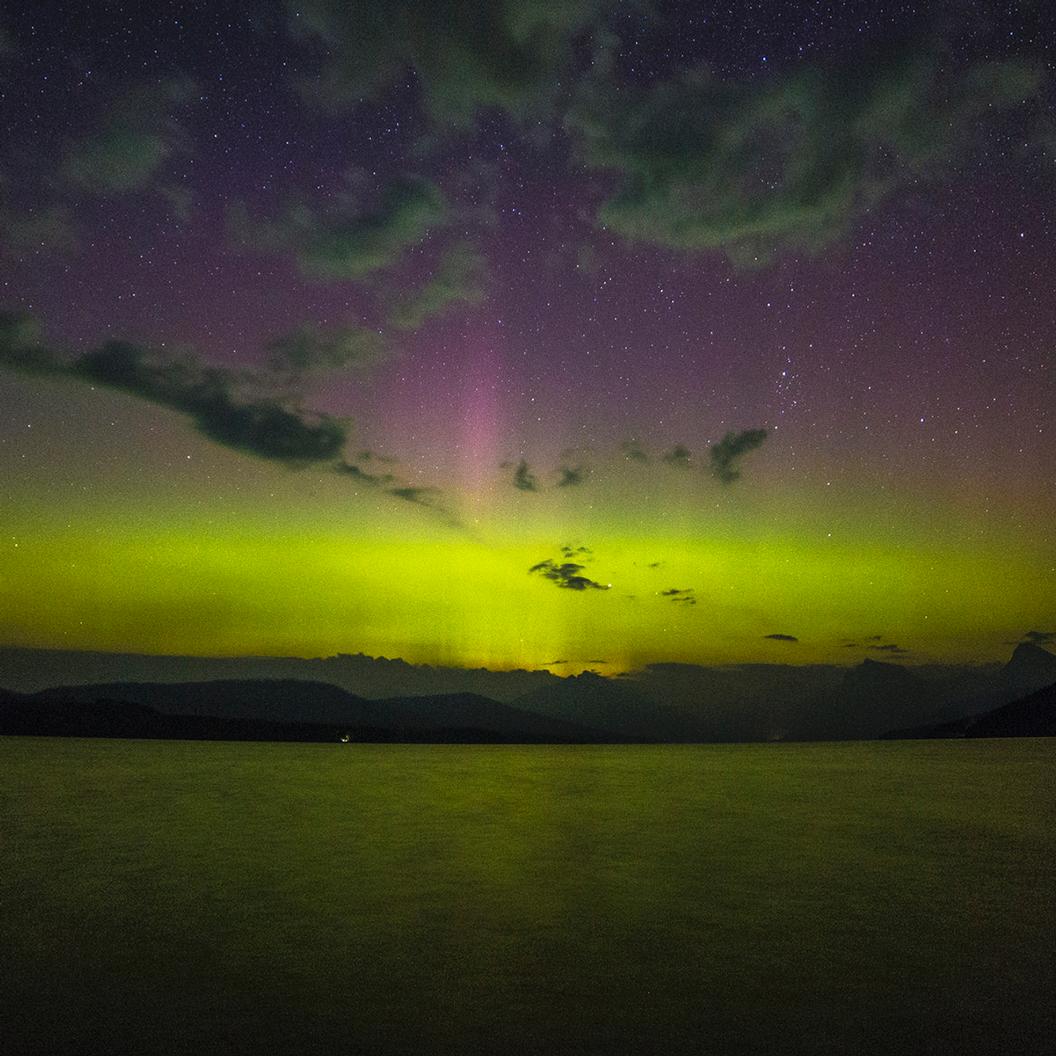beams of light, colors, and clouds in night sky over lake