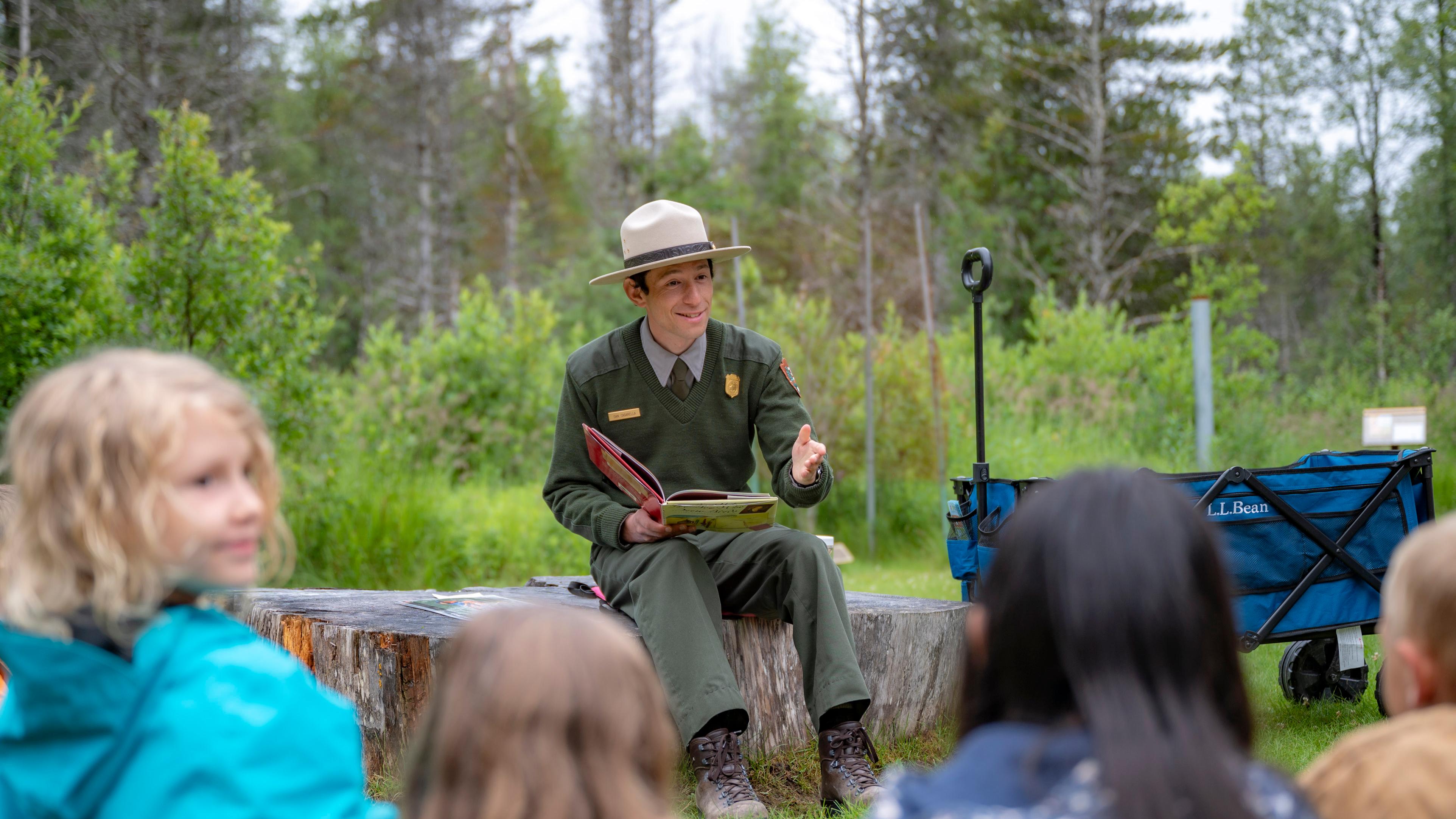 A park ranger speaks to a group of onlooking children