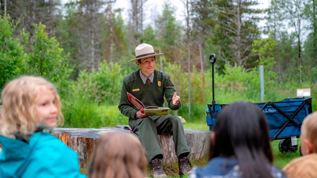 A park ranger speaks to a group of onlooking children