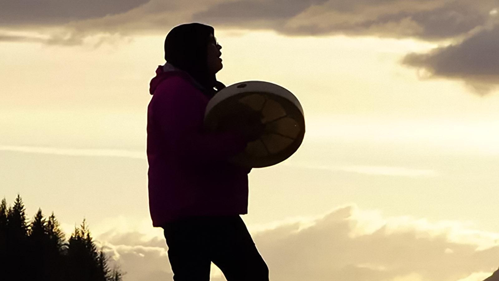 Łing&iacute;t&nbsp;drummer silhouetted against sunset sky
