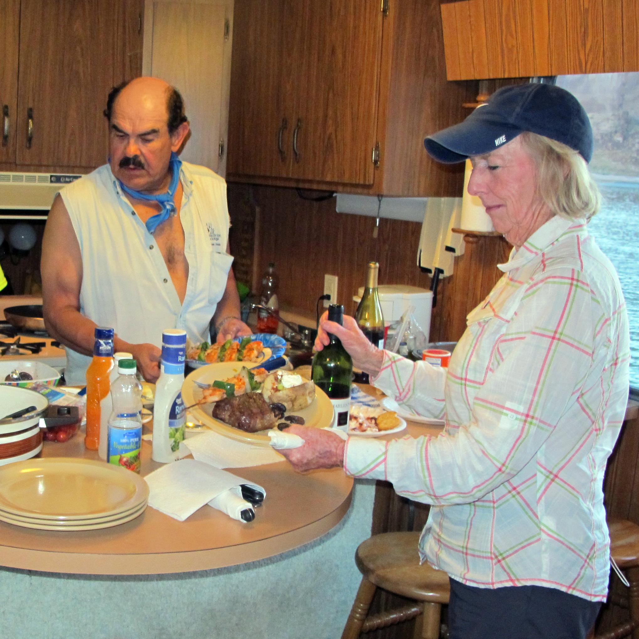 People prepare dinner together in a small houseboat kitchen