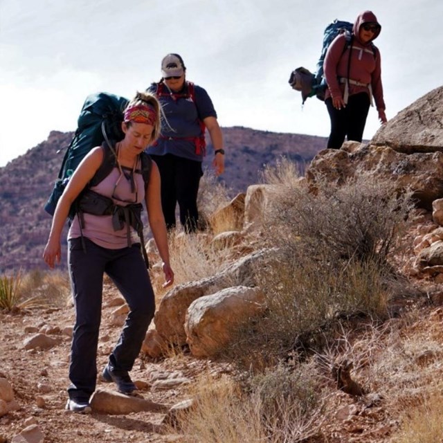 Backpackers climb down a rocky trail 