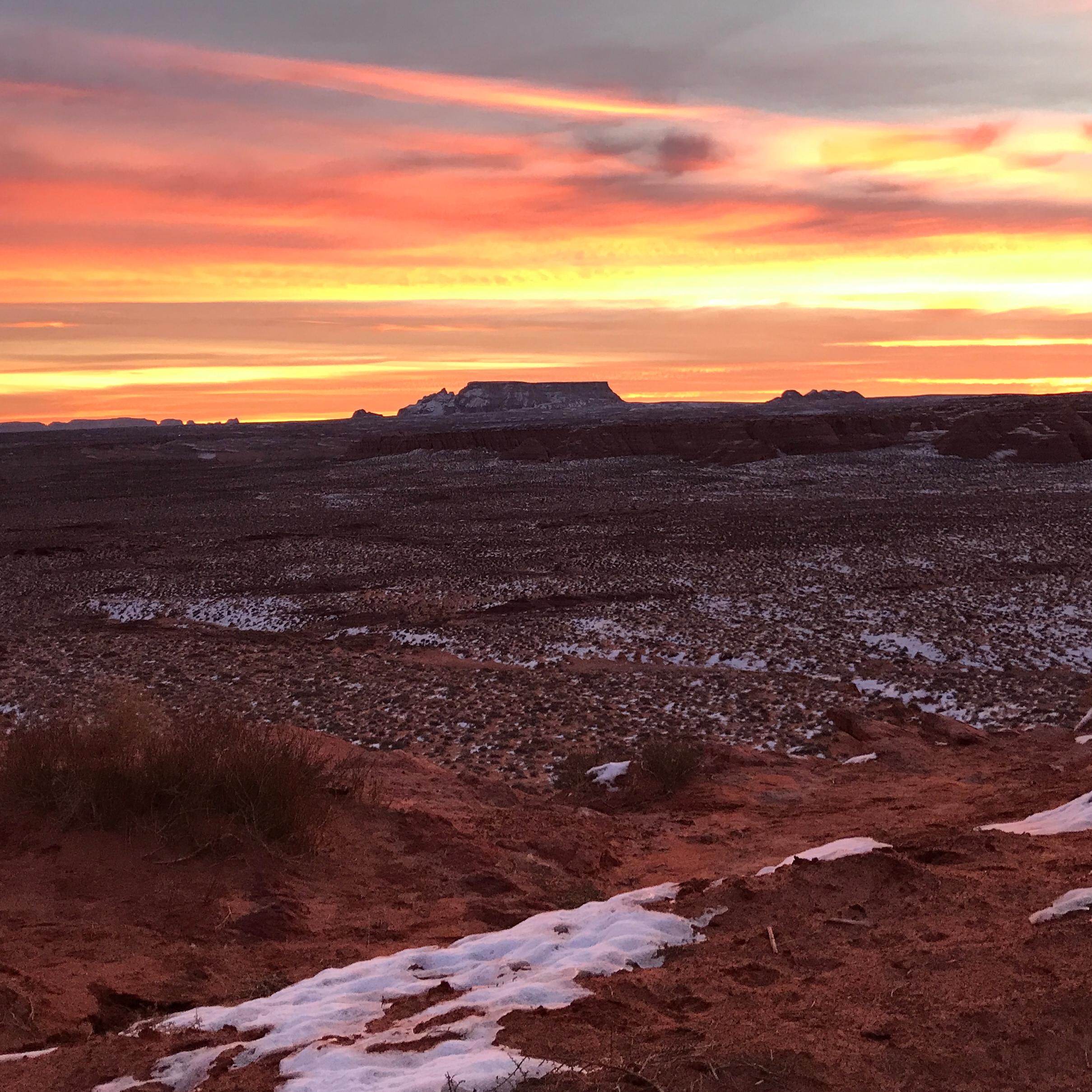 Sunrise over red sand with patchy snow