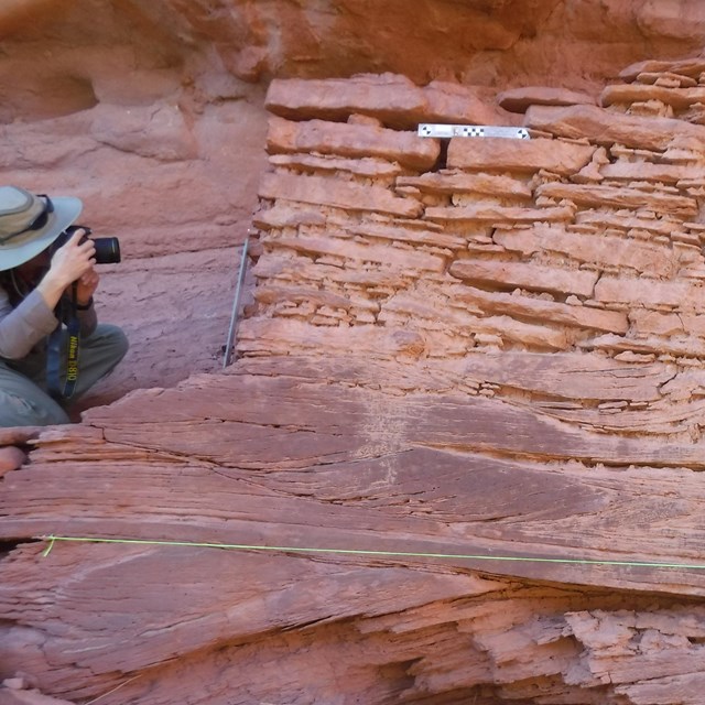 park ranger with scientific measuring tools at an ancient stone masonry structre
