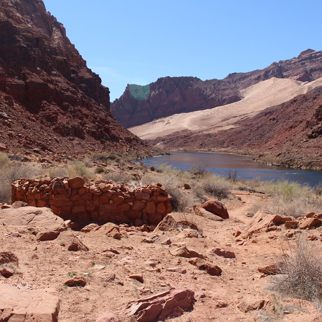 Masonry structure next to a river in a sandstone canyon