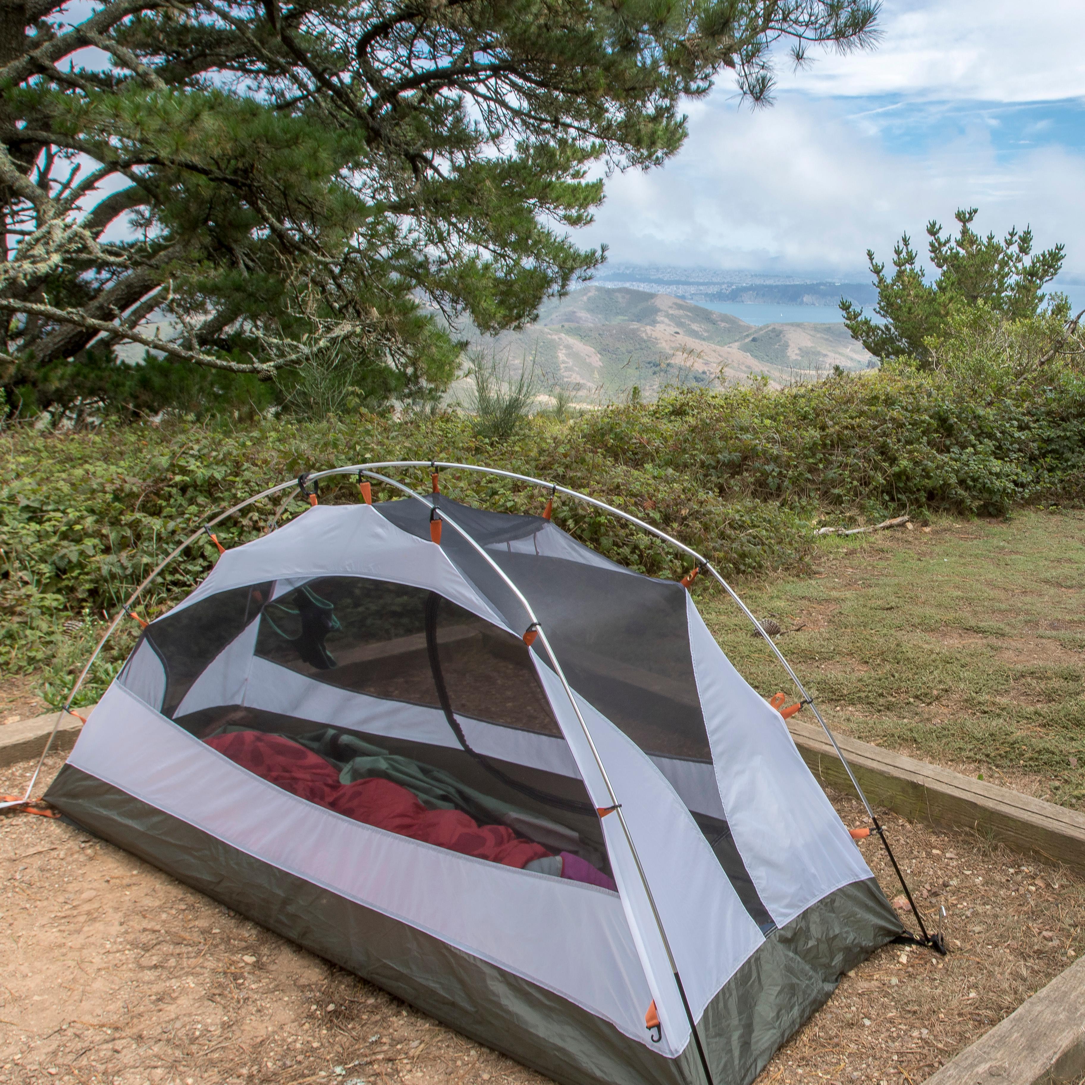A tent is set up on a tent pad, surrounded by trees.
