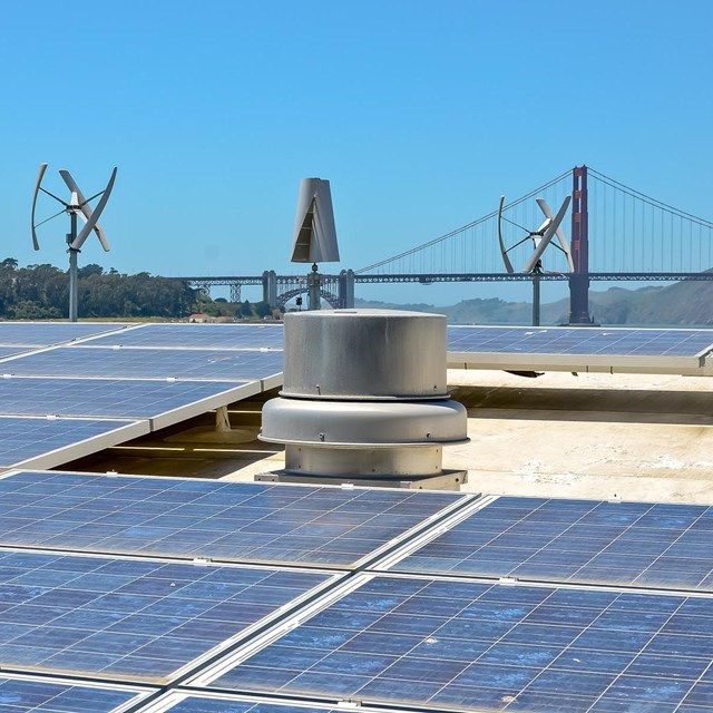 Solar panels on roof by Crissy Field with Golden Gate Bridge in background.