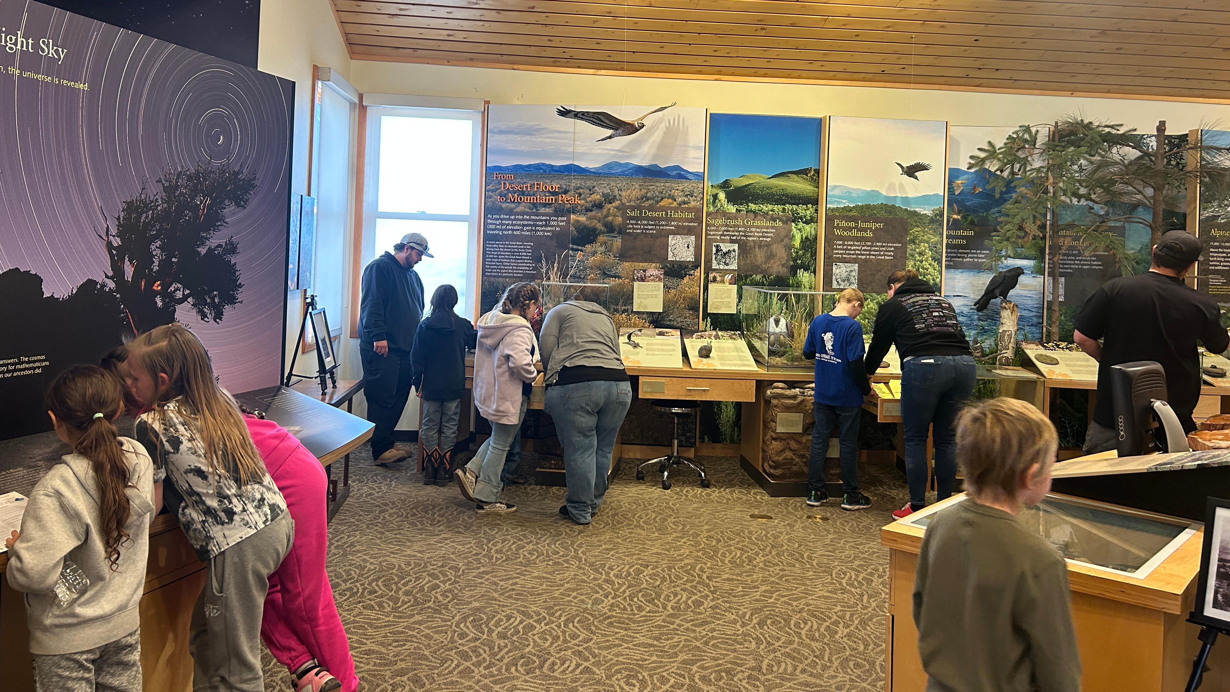 Children and chaperones learning from park exhibits inside a visitor center.