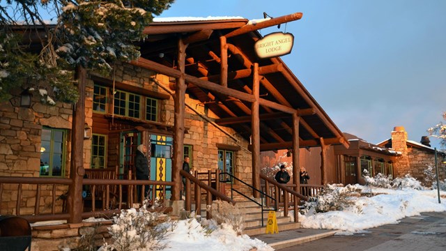 Front entrance to a wood and stone hotel with snow on the ground.