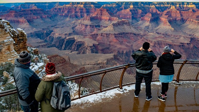 Park Visitors taking photos from standing alongside a guardrail. 