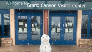A snowman stands outside of the Grand Canyon visitor center doors
