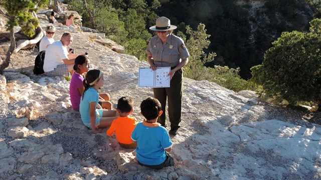 A ranger helps a group of four kids with there Junior Ranger book.