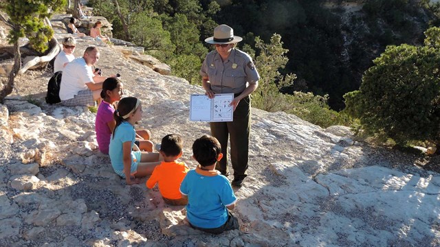 A ranger helps a group of four kids with there Junior Ranger book.