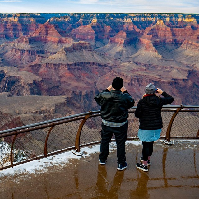 Park Visitors taking photos from standing alongside a guardrail. 