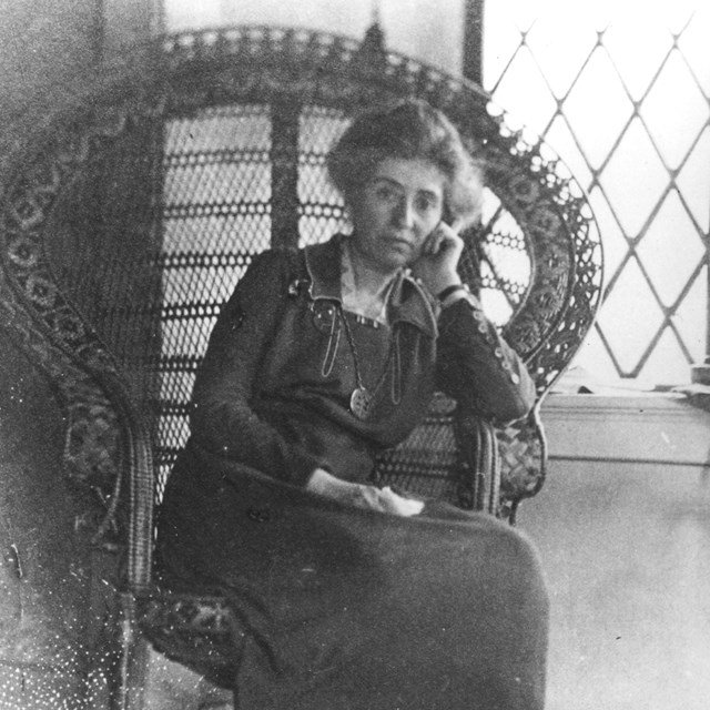A black and white photo of a women sitting in a chair.