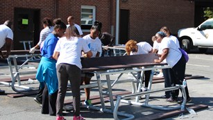 a group of volunteers putting together picnic tables