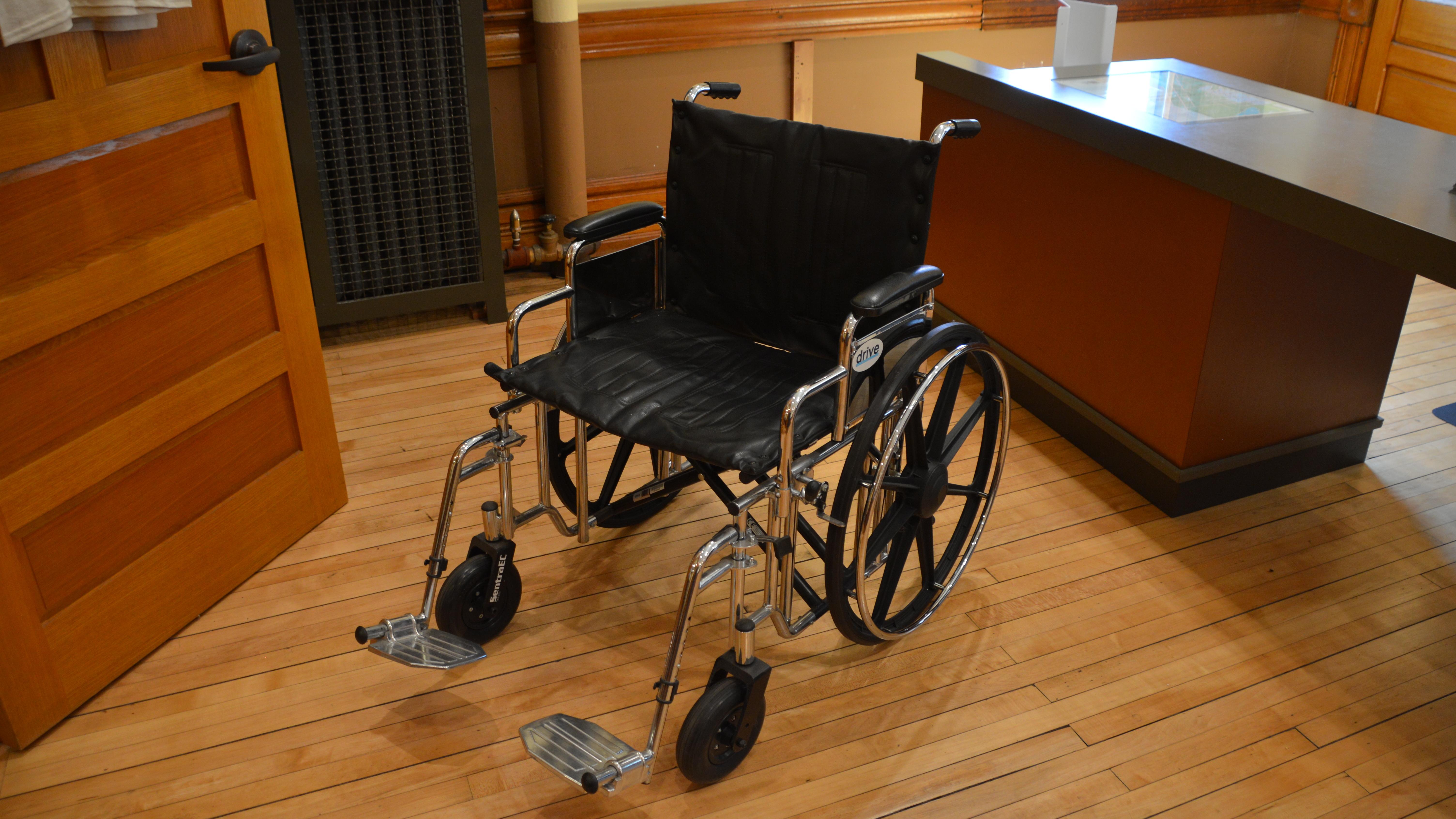 An empty wheelchair in a room with wood floors.