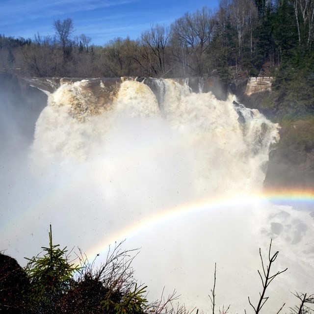 A large waterfall with a rainbow in the spray.