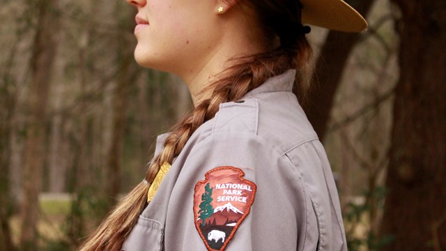 A ranger in a flat hats side profile, showcasing the NPS arrowhead