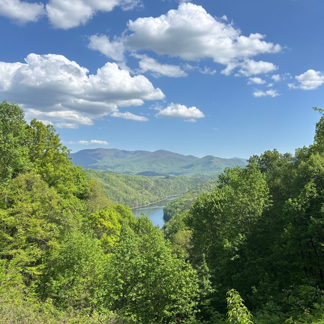 A scenic view of forest and distant mountains and a peak of Fontana Lake.