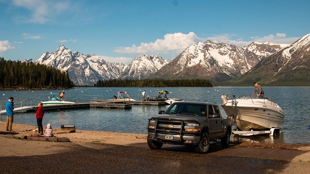 a truck backs a boat into a lake