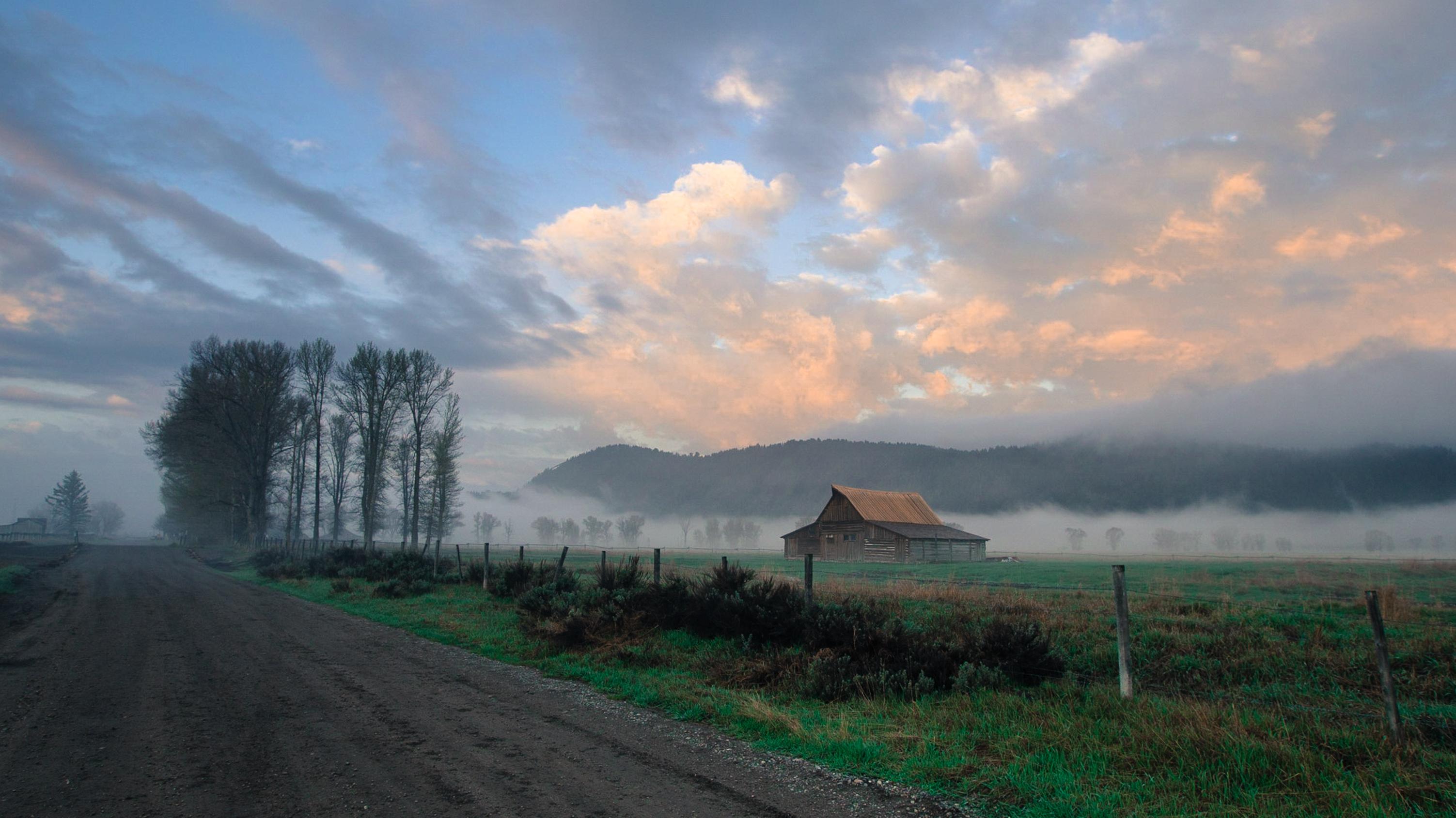 Road going into distance with Mormon Barn under a sun filtered sky