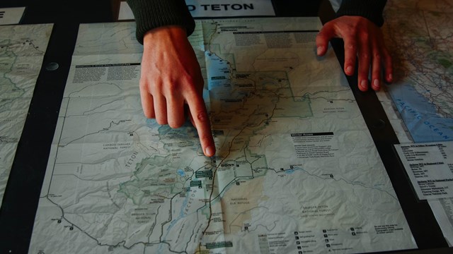 Hands point to a map of Grand Teton.