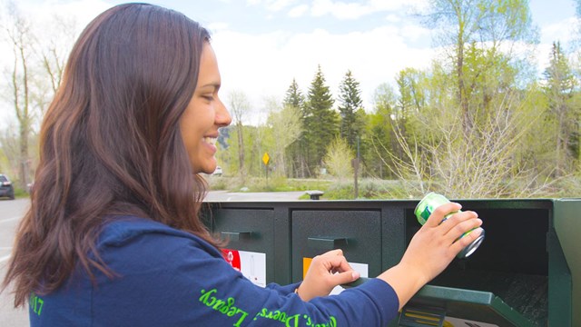 Woman placing a aluminum can in a recycling container.