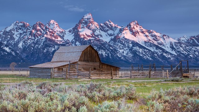 A historic barn in front of the Teton Range