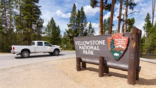 A truck drives past the Yellowstone National Park entrance sign.