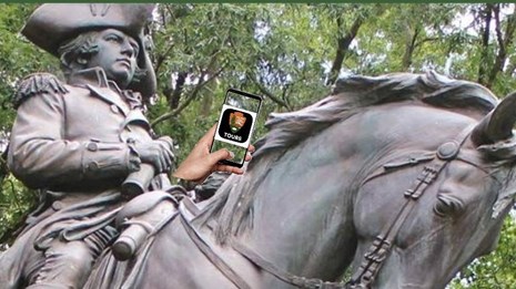 General Greene monument holding an iphone, sitting on horse, forest in foreground