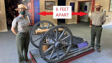 Two park rangers stand 6 feet apart with a 3lb cannon between them.