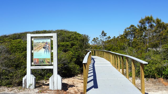 A sign with a wood boardwalk