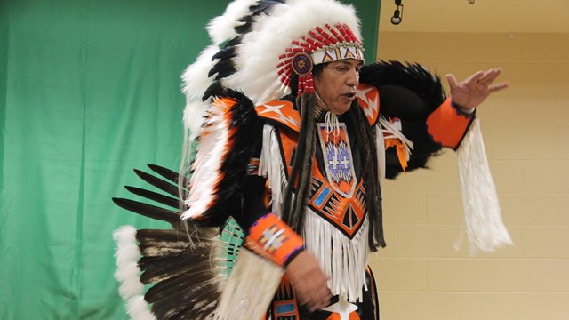 An indigenous man wearing traditional clothing and accessories in many colors. 