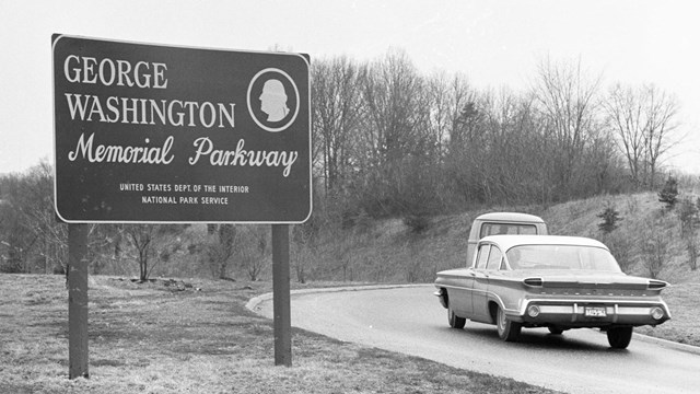 An old 1960s car and sign for the parkway