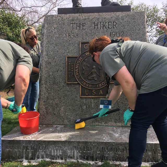 Volunteers cleaning a statue.