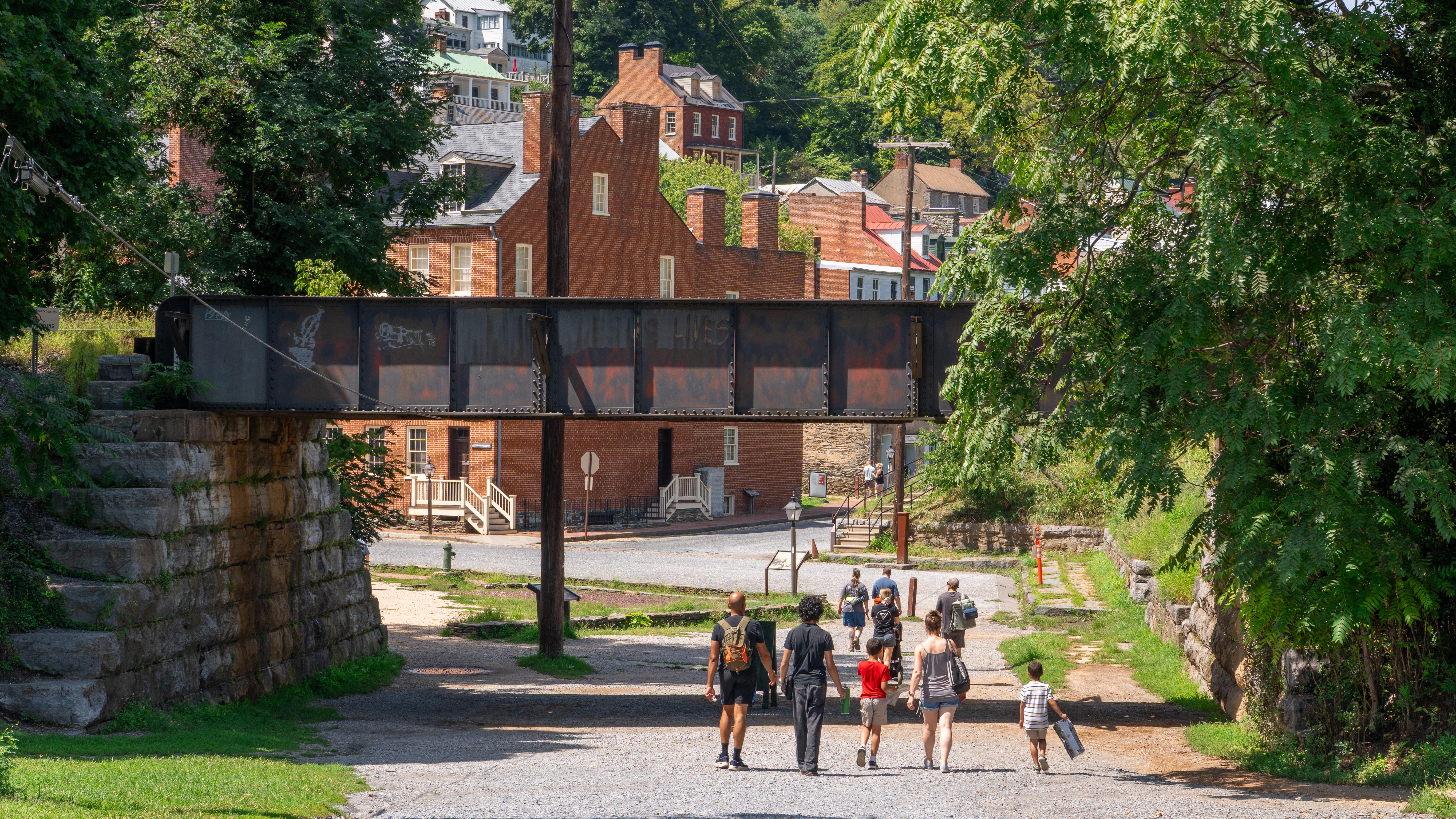 A family walks on a gravel path toward a historic town.