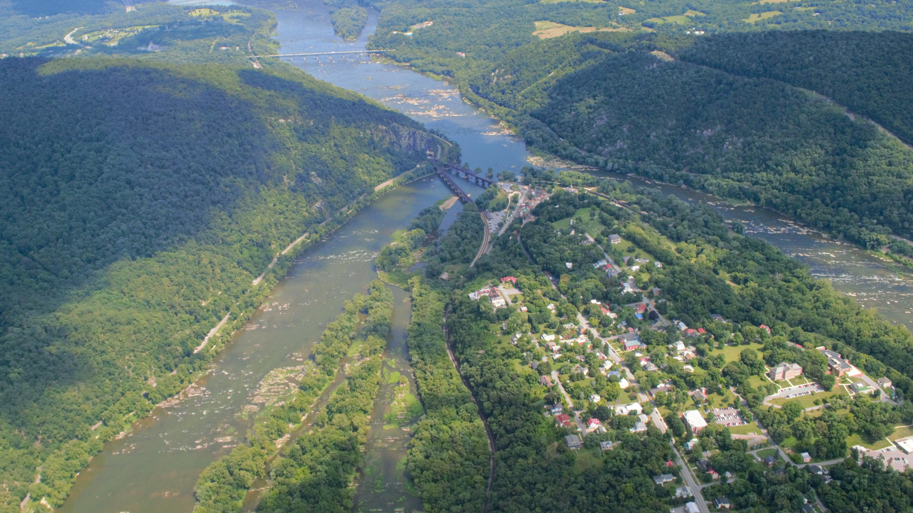 An aerial view of a town, green mountains and two rivers joining.