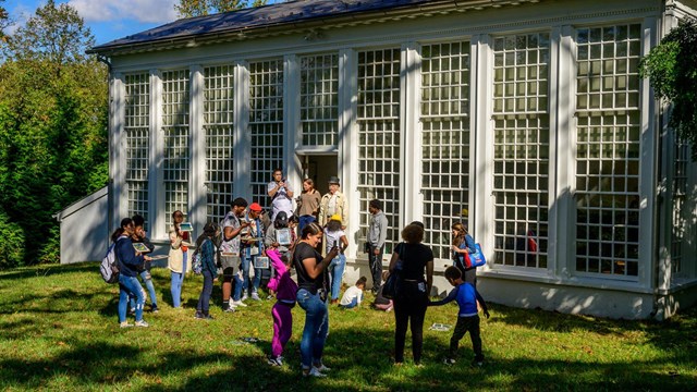A group of people outside of the Orangery, similar to a greenhouse.