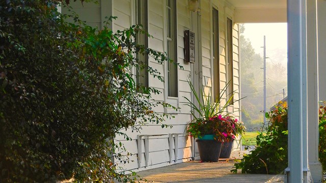 The porch of a white house at dawn.