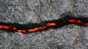 A crack in rock with molten lava shining through