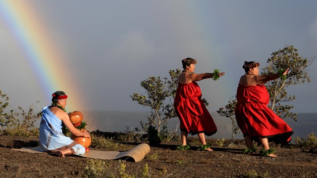 A kumu with drum and hula dances on the rim of a volcanic caldera