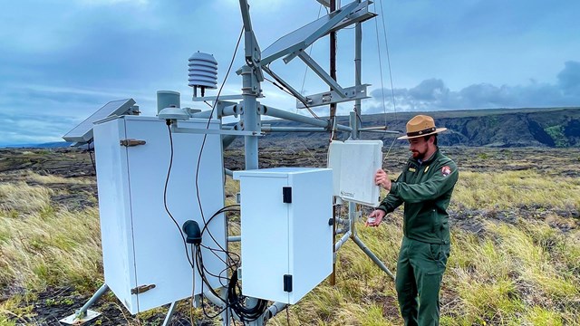 A ranger standing next to a sulfur dioxide monitor. 