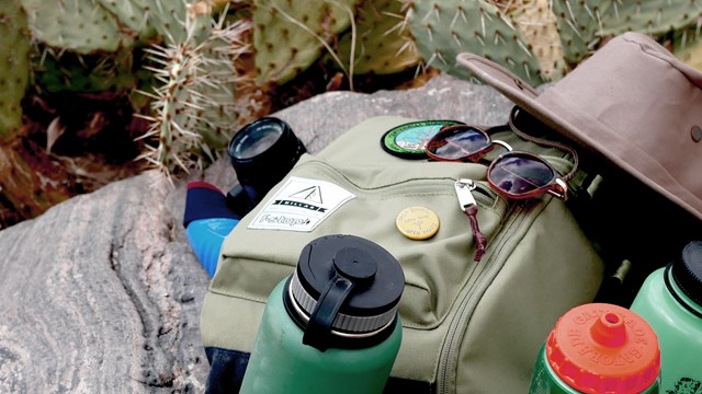 Water bottles, backpack, hat, and sunglasses