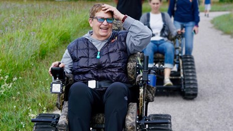 visitor uses accessible wheelchair to enjoy a park trail