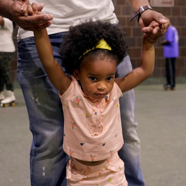 young girl skates with dad at Anacostia Park