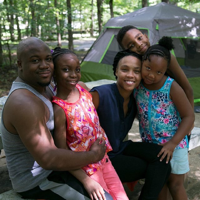 Family of five smiling in front of tent