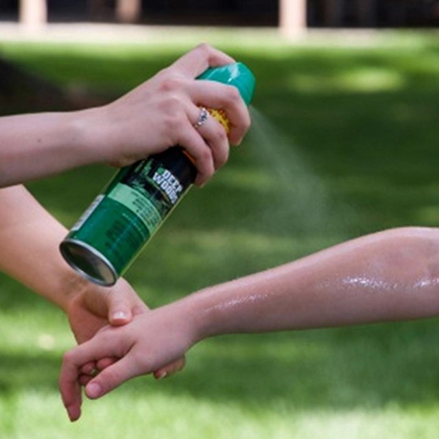 Spraying mosquito repellent spray to arm 