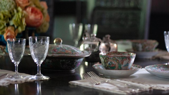 A dining table set with fine linens, flowers, china, and etched crystal glassware.