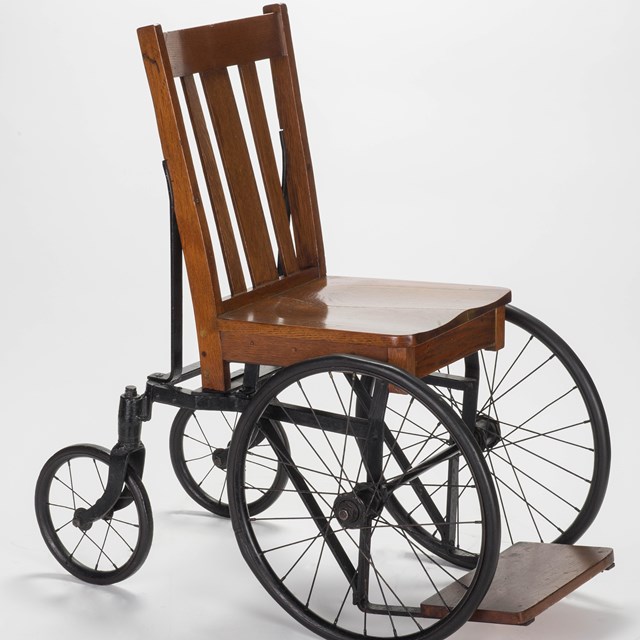 A wood chair mounted on a steel wheelbase.
